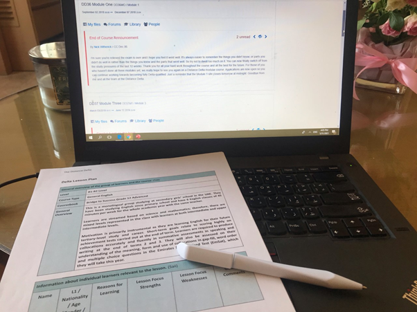 Picture of a laptop on a table with sheets of paper and a pen.